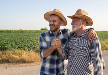 Two farmers shaking hands and hugging in field