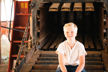 Cute blonde pre-teen boy with relaxed pose in rustic outdoor setting