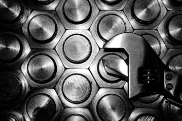 adjustable wrench on the background of hexagonal heads. black and white background.