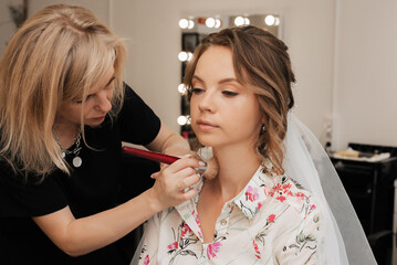 Shooting in a beauty salon. makeup artist makes a wedding makeup for a young girl.
