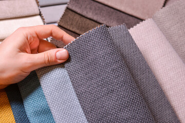 The customer looks at and selects the color fabric she likes, selects the fabric from the fabric swatches for her new sofa.