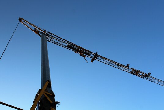 evocative image of the silhouette of a crane on a construction site at dusk 
