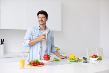 Man in the kitchen with orange juice while preparing a breakfast of vegetables. Vegetarianism