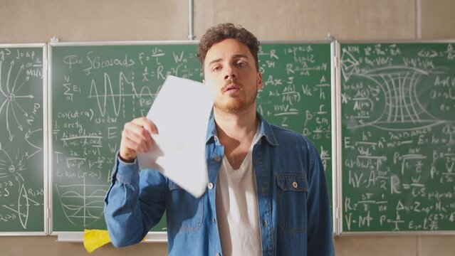 Young teacher fanning paper sheets in a very hot classroom