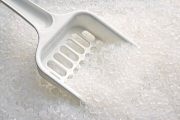 Close-up of silica gel filler and scoop in a cat litter box.