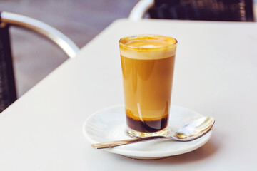 Latte coffee in a small glass coffee cup on a table 