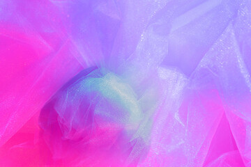 Fashion blog concept. Light pink tulle fabric enlightened with two colors – blue and red. Background from pink crumpled tulle. Textured background for atelier.