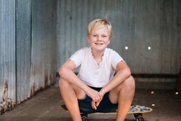 Cute blonde pre-teen boy with relaxed pose in rustic outdoor setting