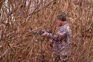 professional photographer in camouflage outfit is hidden in nature