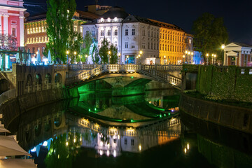 Picturesque night view of illuminated Triple Bridge and Mayer Palace in Ljubljana, Slovenia