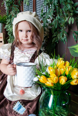 Charming cute European girl with brown eyes watering tulip flowers in a Disney Cinderella costume....