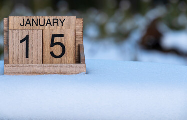 Wooden calendar of January 15 date standing in the snow in nature.