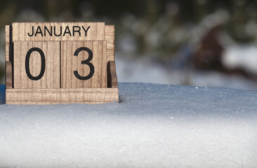 Wooden calendar of January 3 date standing in the snow in nature.