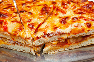 Sliced pizza slices on a tray with a lot of cheese, close-up.