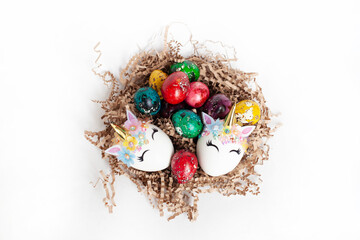 traditional Easter decoration. multicolored quail eggs and two white unicorn eggs in a nest on a white background. top