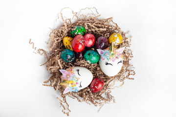 Fototapeta na wymiar traditional Easter decoration. multicolored quail eggs and two unicorn eggs in a nest on a white background