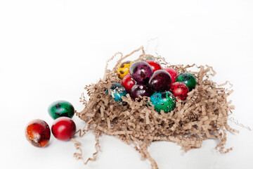 traditional Easter decoration. multicolored bright quail eggs in a nest on a white background.