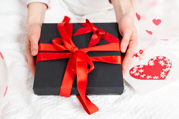Gift box packed and decorated with a red beautiful bow on the bed. Valentine's day, Birthday love gift. Weeding, honey moon concept. Lovers or romantic celebrating atmosphere
