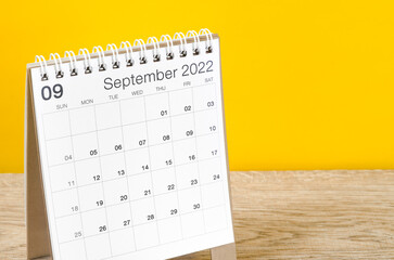 September 2022 desk calendar on wooden table with yellow background. - obrazy, fototapety, plakaty