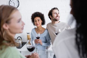 happy multiethnic couple near lesbian women on blurred foreground.