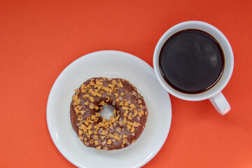 One chocolate donut and black Americano coffee without milk in a white cup on a bright background....