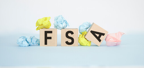 Concept words FSA, flexible spending account on wooden cubes on a beautiful green background.