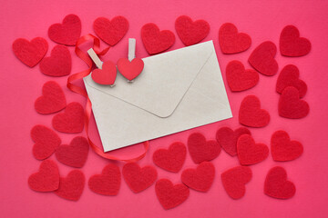 Background for your greetings for a Valentine's day. A envelope with felt hearts on the red background. Top view.
