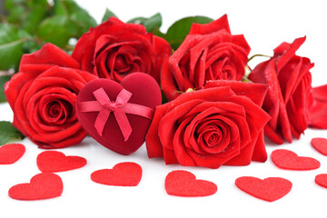 Red rose bouquet with heart-shaped gift box and red felt hearts on white background. Soft focus.