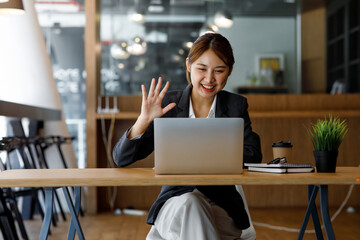 Shot of Asian young business woman looking and speaking through the webcam while making a video conference from the office.