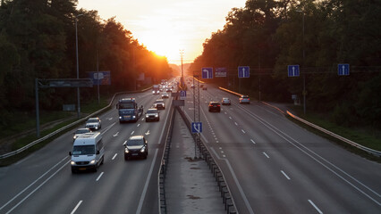 Moving cars on the motorway at sunset time. Highway traffic at sunset with cars. Busy traffic on the freeway, road top view.