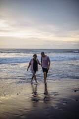 young beautiful couple in love walking at sunset by the ocean, couple relaxing in Bali, vacation in Bali, travel together, hug, love