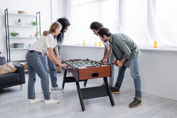 happy interracial women and man playing table football.