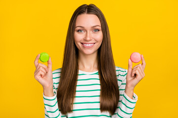 Photo of sweet pretty lady dressed striped shirt choosing green pink cookies isolated yellow color background