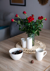 Coffee with sweets on the table, a vase with red roses and candles. Beautiful still life