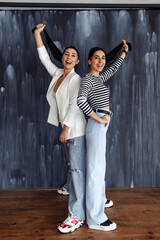 Studio shot of girlfriends with black hair on a gray background.