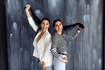 Studio shot of girlfriends with black hair on a gray background.