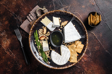 Cheese plate with brie and camembert on rustic plate with nuts and honey. Dark background. Top view