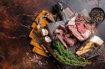 Braised veal beef short ribs on wooden cutting board with thyme. Dark background. Top view. Copy...