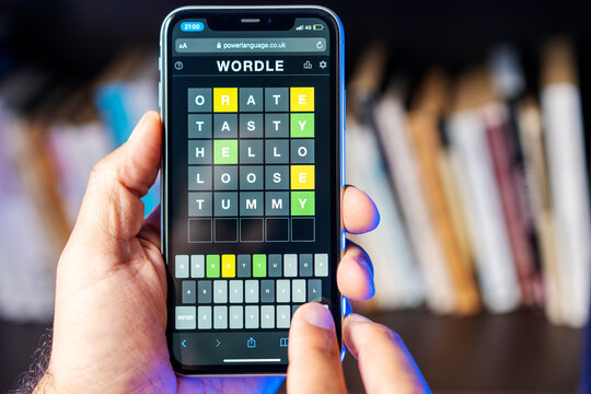 person holding a cellphone with Wordle game, hands view, close up