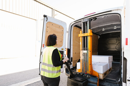 Anonymous woman loading boxes with stacker