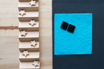 small wooden stars on a wooden object, with paper, tiles, and fabric