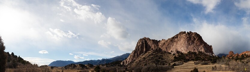 Panorama of a massive rock outcropping before a ridge of the Rocky Mountains, Colorado American west with dramatic clouds, horizontal aspect