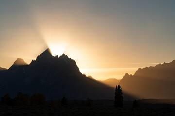 Sun rays reaching out from behind the Grand Tetons at sunset