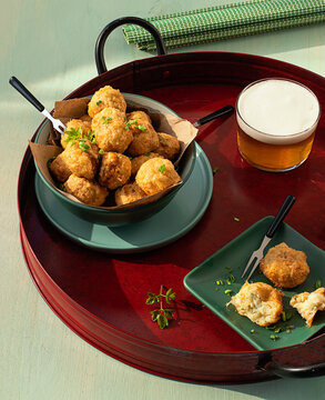 Codfish fritters server on tray with fresh herbs and glass of beer