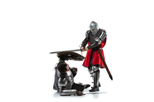 Full-length portrait of two medieval warriors, knights fighting isolated over white studio background