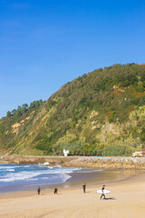 Fototapeta na wymiar Surfer with surfboard walking on the Zurriola beach in San Sebastian