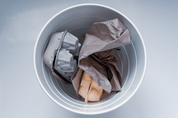 Paper garbage in a white trash can on a white background