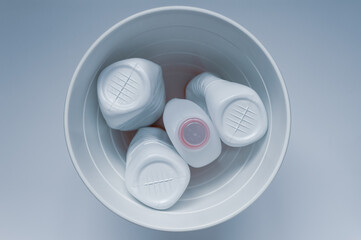 White plastic bottles in a trash can on a white background