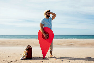 Traveling man with red map pointer on seashore