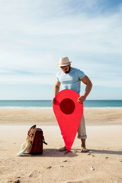 Traveling man with red map pointer on seashore